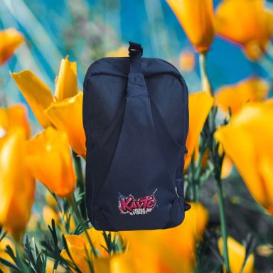 Schwarzer Rucksack vor leuchtenden orangen Blumen.